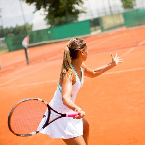 Pretty female tennis player playing on court on a sunny day